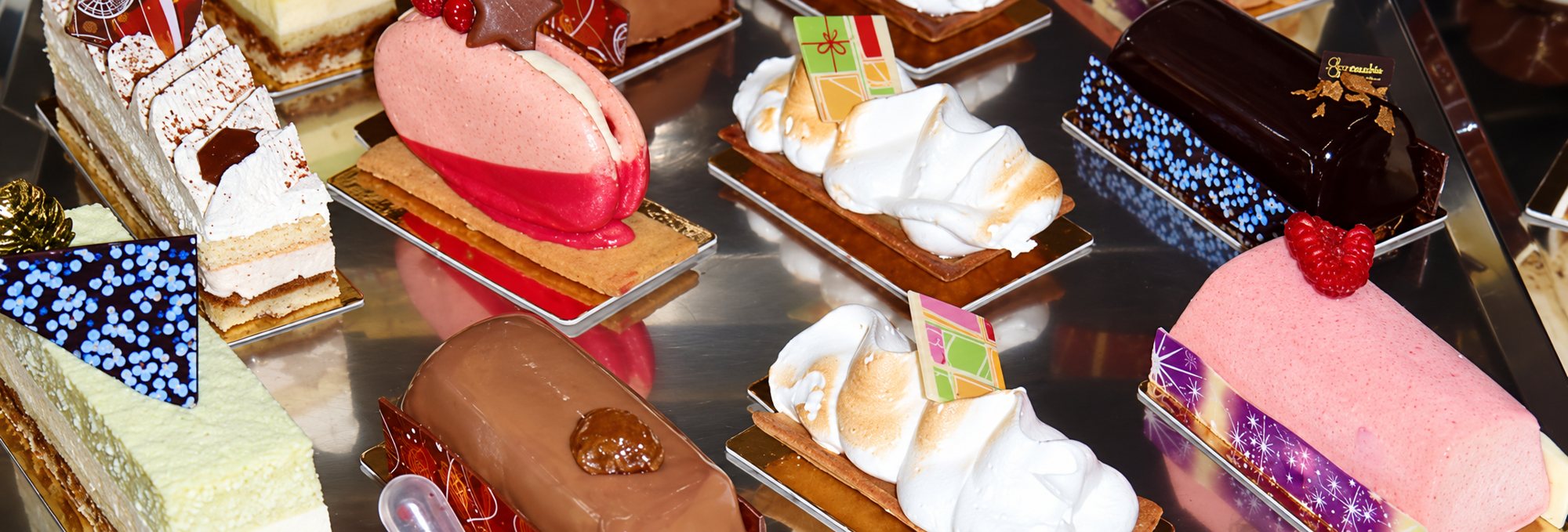 Plusieurs petites pâtisseries individuelles, meringuées, chocolatées et aux fruits rouges, présentées sur des supports dorés et argentés.