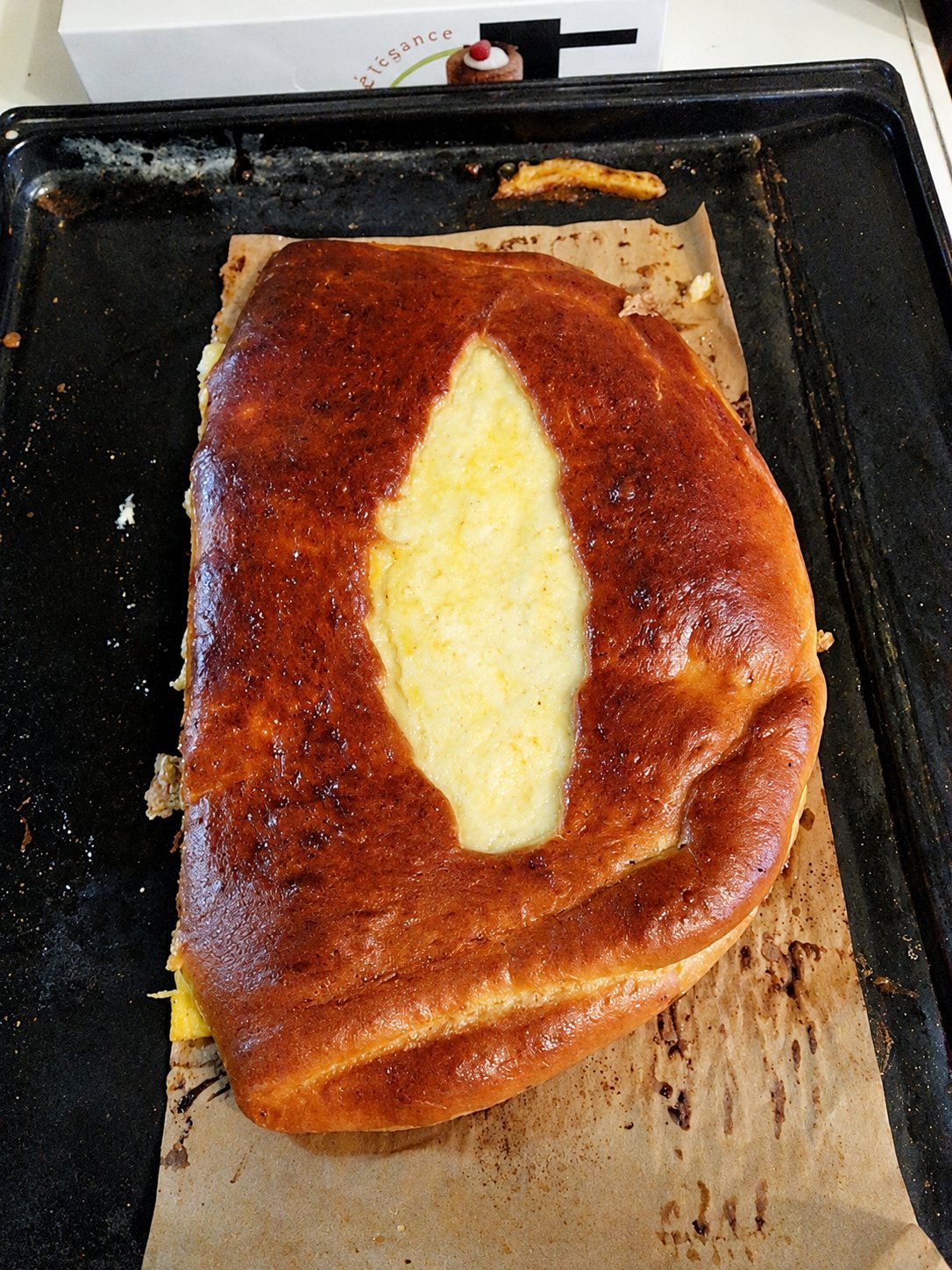 Brioche dorée garnie de fromage sur une plaque de cuisson.