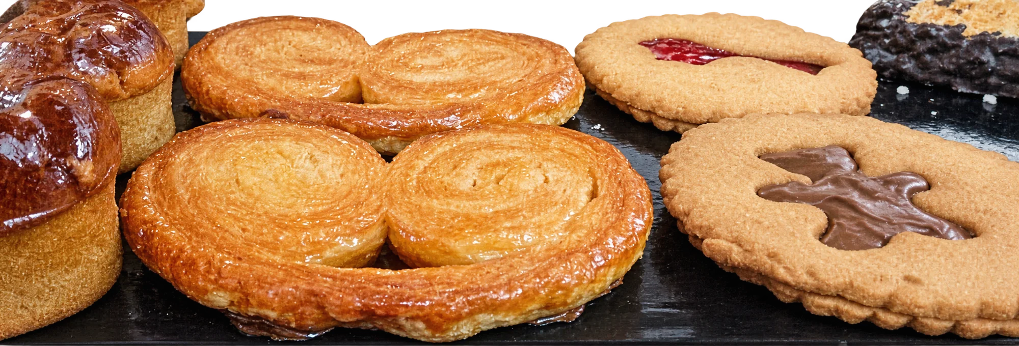 Palmiers, sablés fourrés à la confiture et au chocolat sur un plateau noir