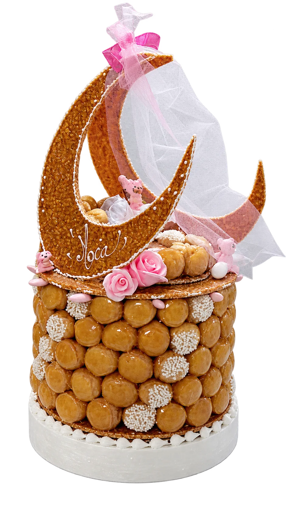 Une pièce montée ronde en choux caramélisés, décorée de grands croissants de lune dorés, de roses roses et d'un voile en tulle, posée sur une table en marbre.