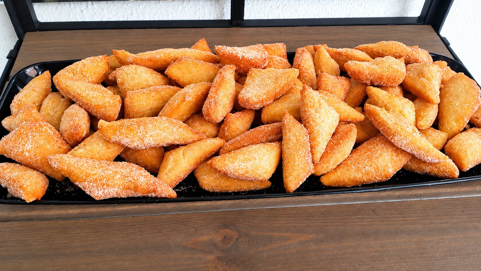 Plateau de beignets triangulaires sucrés sur une étagère en bois